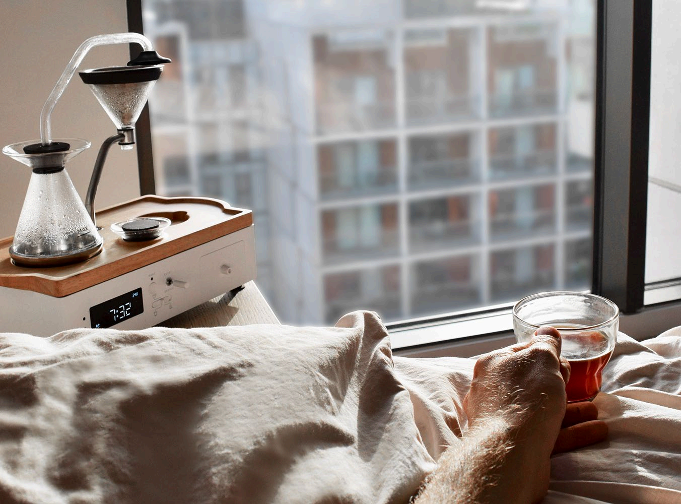 The Barisieur coffee and tea brewing alarm clock on a bedside table at sunrise.